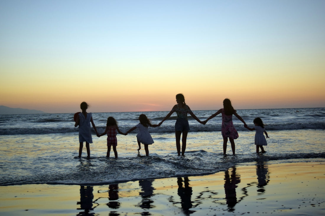 a family holding hands on the beach at sunset