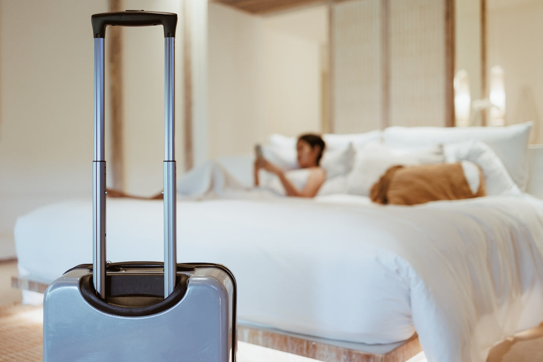 a woman laying on a bed with a suitcase in front of her
