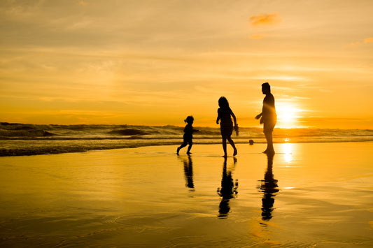 a family walking on the beach at sunset