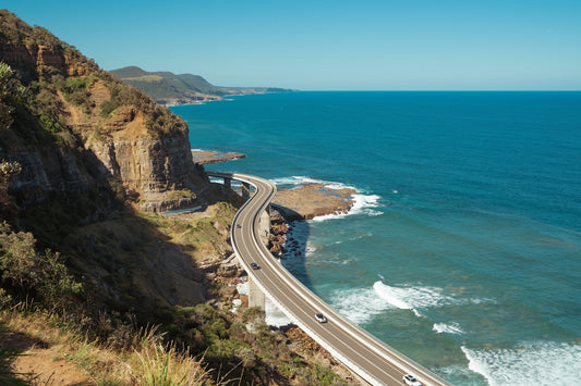 A car driving down a road next to the ocean