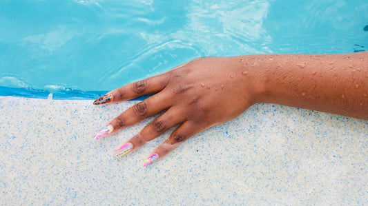 A woman's hand resting on the edge of a swimming pool
