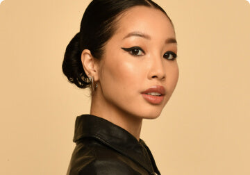 a woman wearing a tie standing in front of a wall 